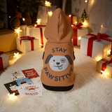 Dog hoodie with 'Stay Pawsitive' text and dog graphic in a festive setting with lights and presents.